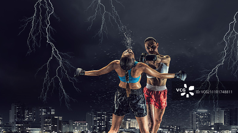 户外女子拳击：两位年轻漂亮的女人在夜景城市背景下拳击图片素材