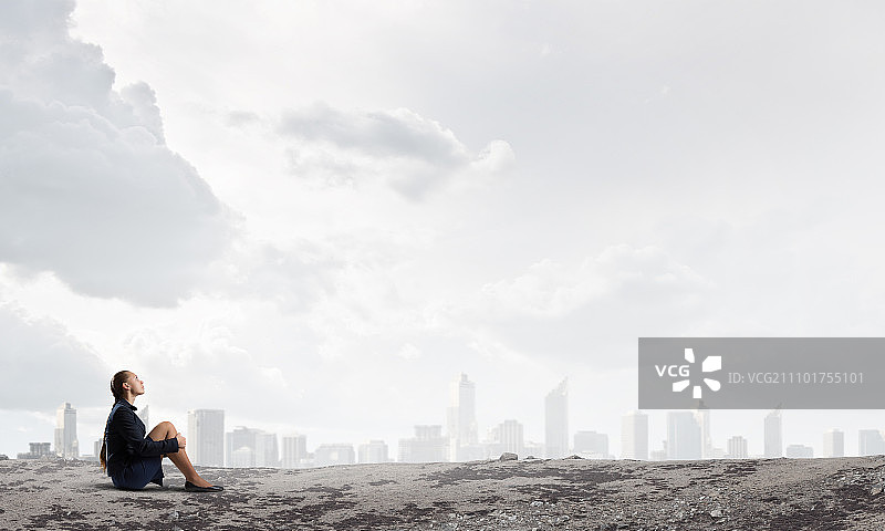 她感到绝望和孤独：一位沉思的年轻女商人独自坐在岩石顶上图片素材