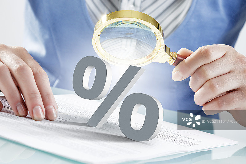 使用放大镜进行探索的人物：商务女性用放大镜查看百分比符号的特写图片素材