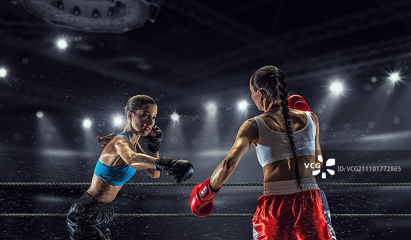 拳击擂台上的女孩。两位年轻漂亮的女人在擂台上拳击图片素材
