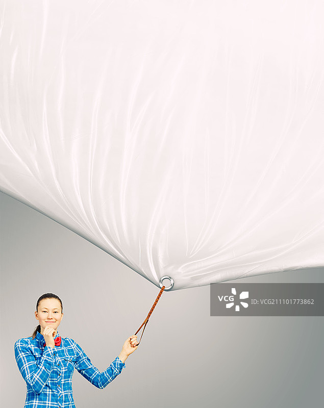 拿着banner的女人。穿着休闲的年轻女人拉着白色空白banner。文字位置图片素材