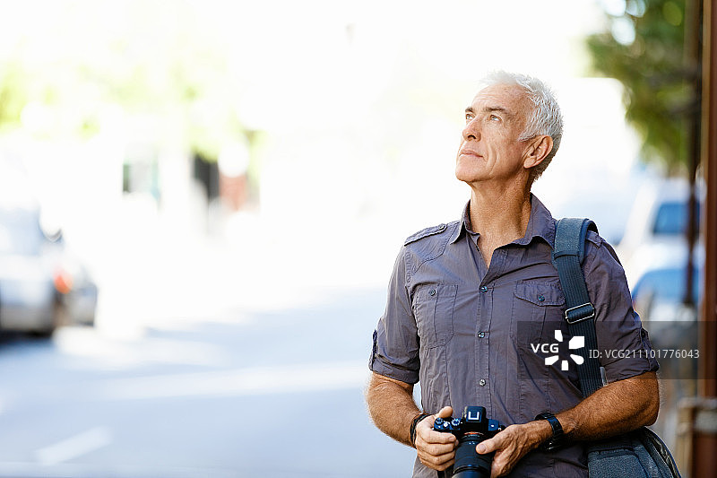 在城市里寻找拍摄地点的年长男人图片素材