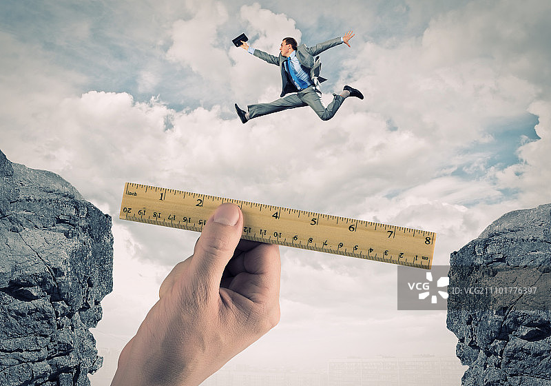 勇敢的商人。身穿西装的年轻商人跳过山间图片素材