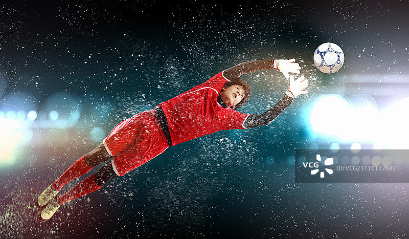聚光灯下的体育场里，守门员接住了球图片素材