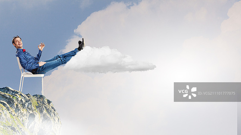 放松的男人。年轻人坐在椅子上，抬起腿放松图片素材