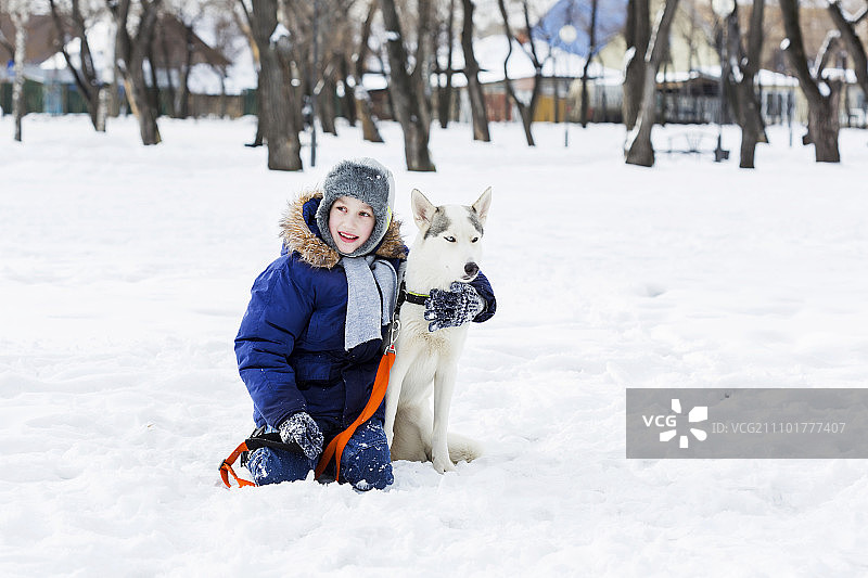 学龄儿童与小狗在冬季公园里，我最好的朋友和我图片素材
