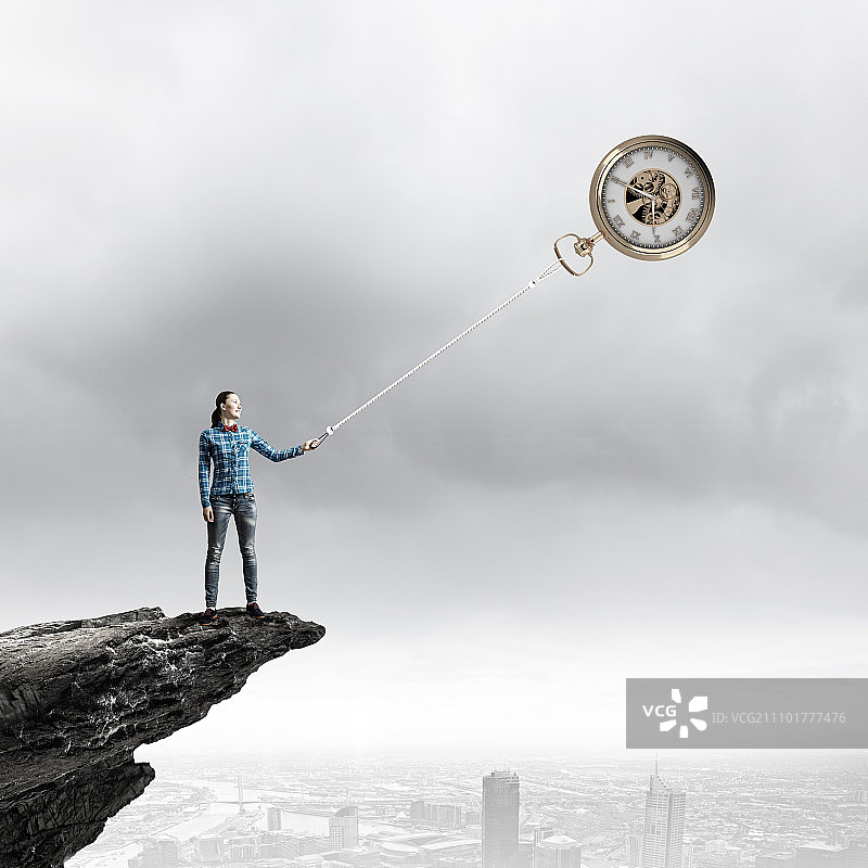 时间流逝：休闲装扮的年轻女子用绳子抓住时钟图片素材