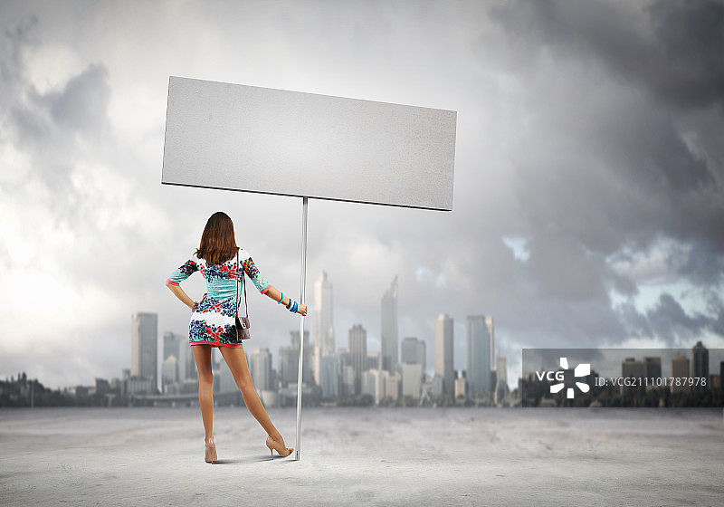手持banner的女人。年轻有魅力的女人手持空白banner的背影图片素材