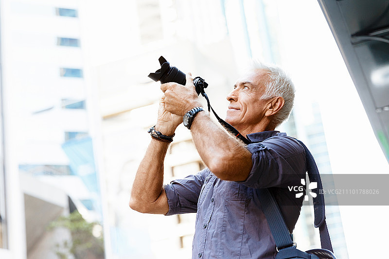 在城市里寻找拍摄地点的年长男人图片素材