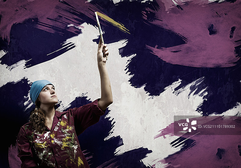 用画笔的妇女：年轻女性用刷子给墙壁上色图片素材