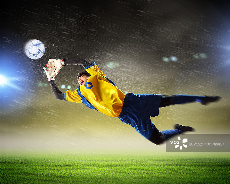 聚光灯下的体育场里，守门员接住了球图片素材