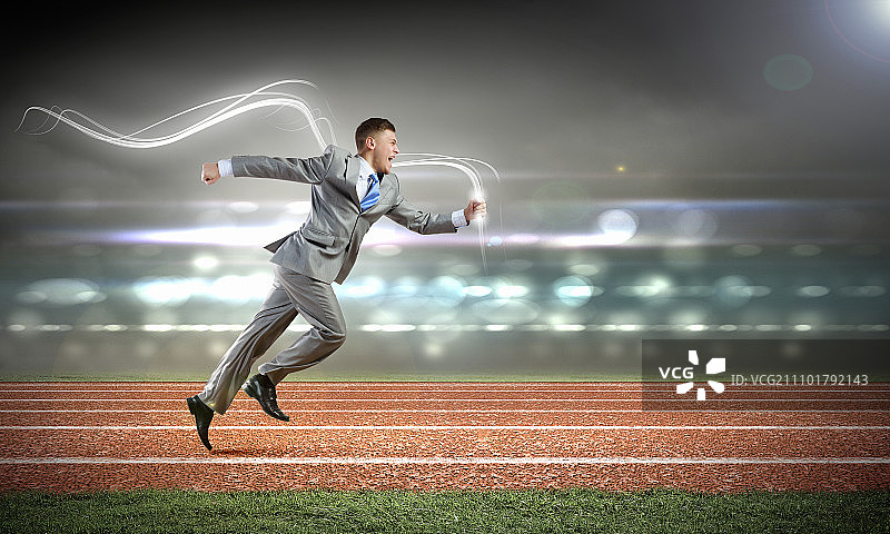 商业竞争：身穿西装的年轻商人奔跑在体育场跑道上图片素材