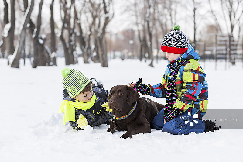 在冬季公园里和狗玩耍的学龄儿童图片素材