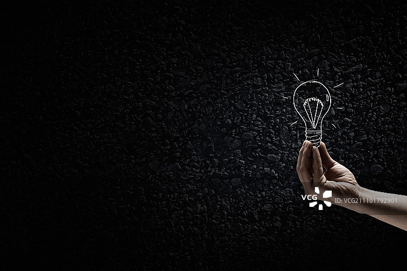 黑暗中的光芒：黑暗背景中手持灯泡图片素材