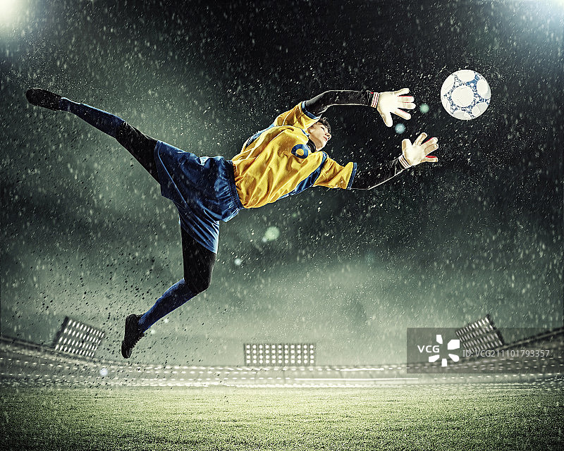 聚光灯下的体育场里，守门员接住了球图片素材