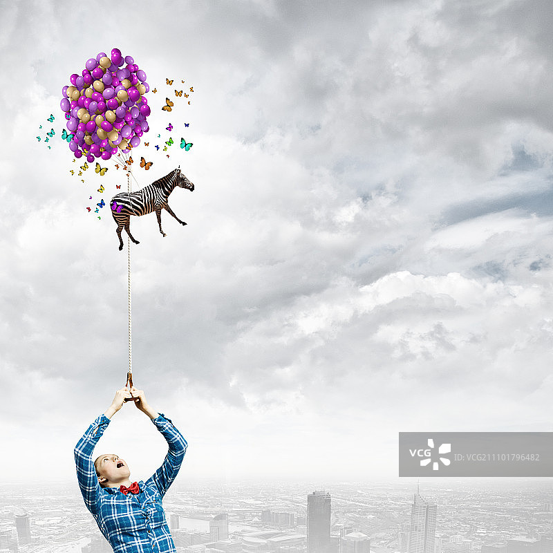 牵着斑马的年轻女人和在空中飞翔的斑马图片素材