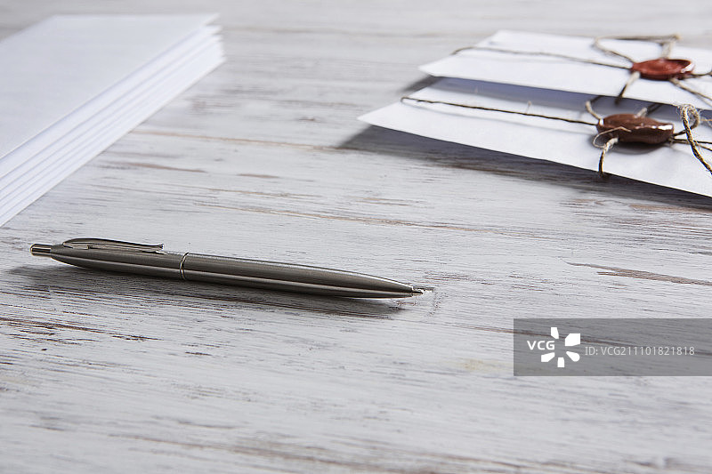 桌上带有封印的信件：带有蜡封的信封和木质表面上的空白纸张图片素材