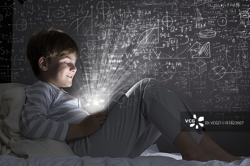 在床上使用平板电脑的可爱小男孩图片素材