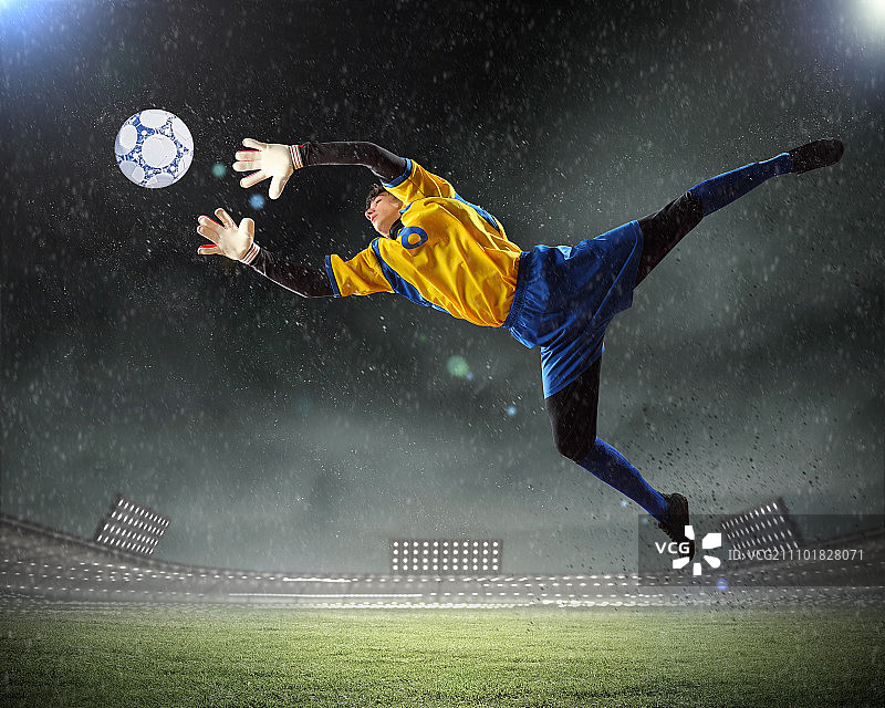 聚光灯下的体育场里，守门员接住了球图片素材