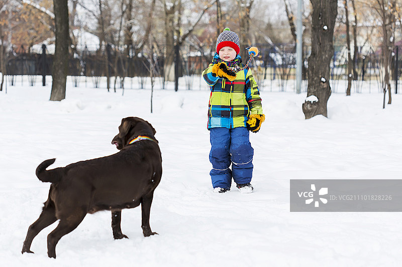 学龄儿童与小狗在冬季公园里，我最好的朋友和我图片素材