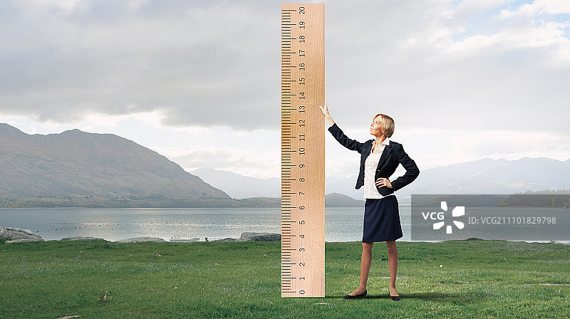 年轻女商人用大尺子测量某物图片素材