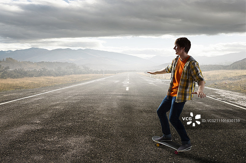 男孩玩滑板：在沥青路上玩滑板的活跃男孩图片素材