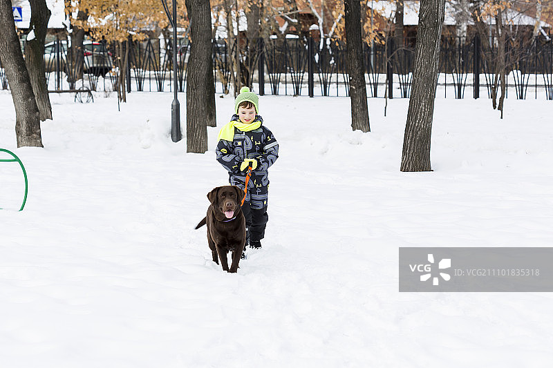 学龄儿童与小狗在冬季公园里，我最好的朋友和我图片素材