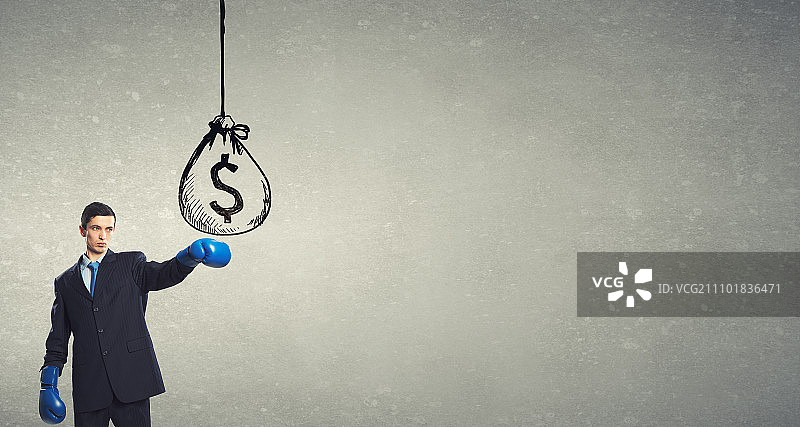 他准备为成功而战。年轻商人戴着拳击手套击打钱袋图片素材