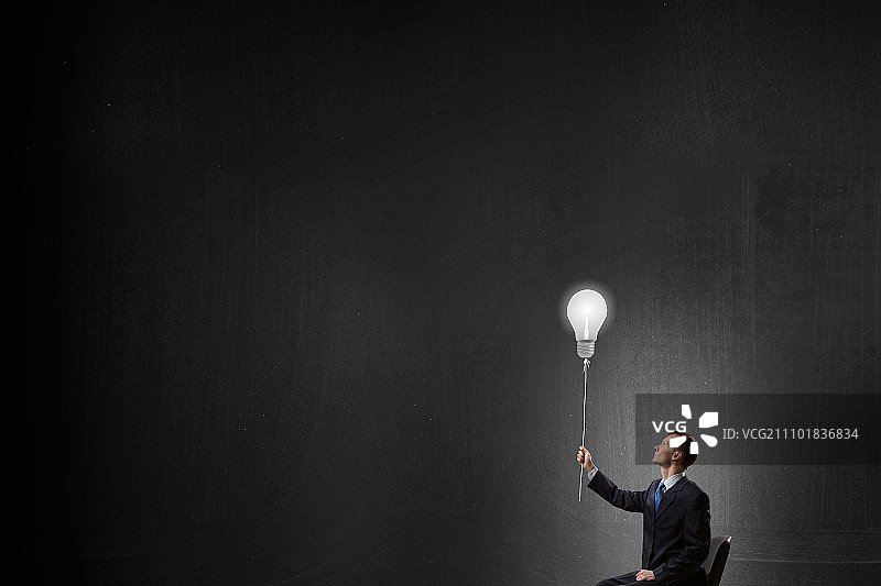 商人拿着灯泡，象征着绝妙的主意图片素材