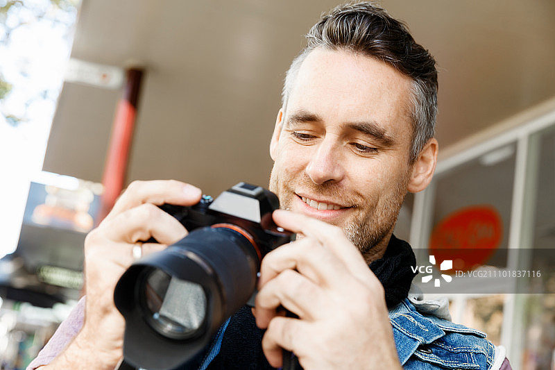 男摄影师正在拍照。专业摄影师在城市拍照图片素材