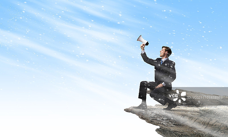 商人宣布某事。坐在岩石边缘对着扩音器尖叫的商人图片素材