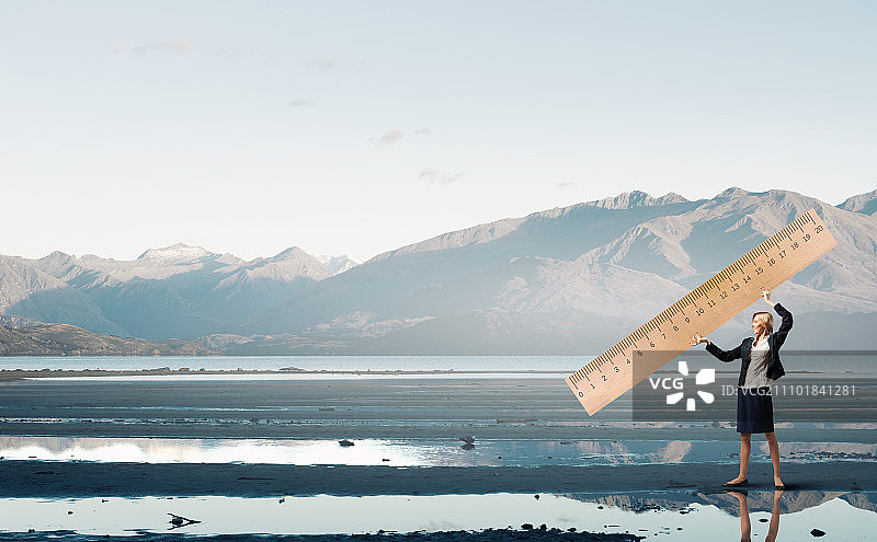 年轻女商人用大尺子测量某物图片素材