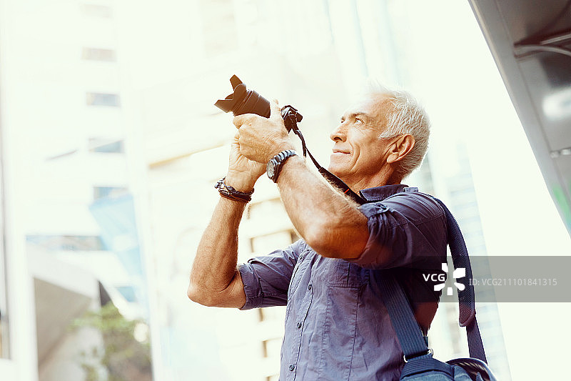 在城市里寻找拍摄地点的年长男人图片素材