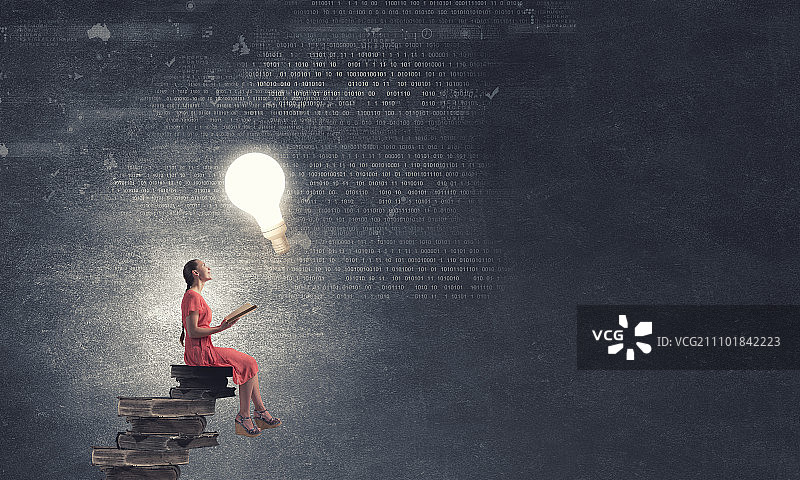 拿着书的连衣裙女人。坐在书堆上阅读的年轻女孩图片素材