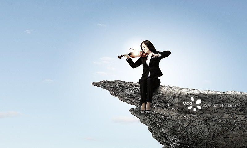 悬崖边演奏小提琴的年轻女子图片素材