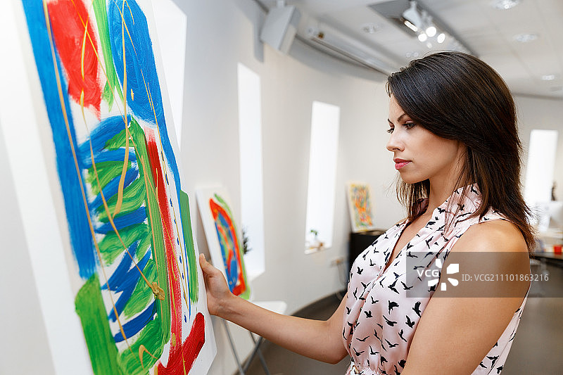 年轻的白人女子站在美术馆的画作前图片素材