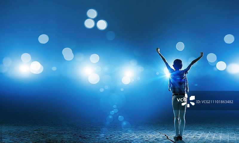 舞台上的表演者：站在舞台灯光下的女孩的背面图片素材