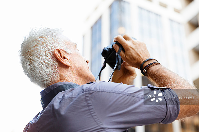 在城市里寻找拍摄地点的年长男人图片素材