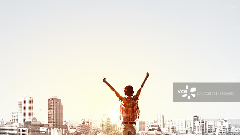 迎接新的一天：女孩举手面对城市日出图片素材