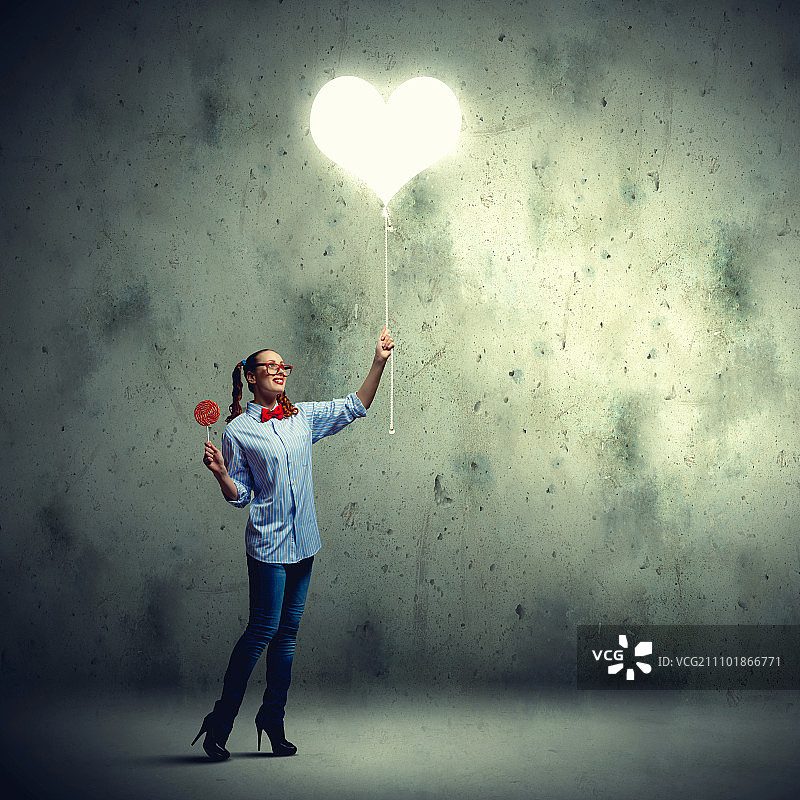 戴红色眼镜吃糖果的少女，爱心概念图片素材