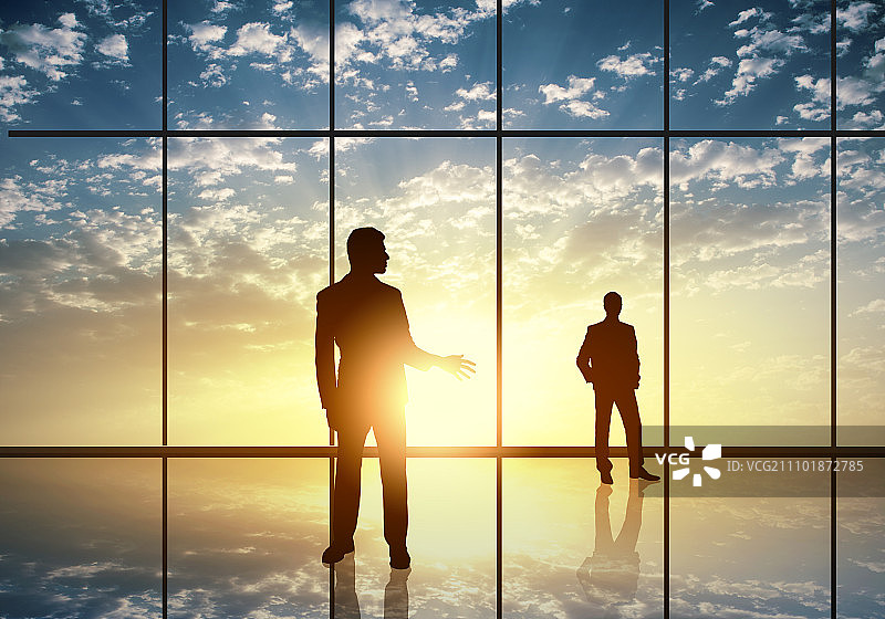 办公室会议：商务人士在全景办公室窗口前的剪影图片素材