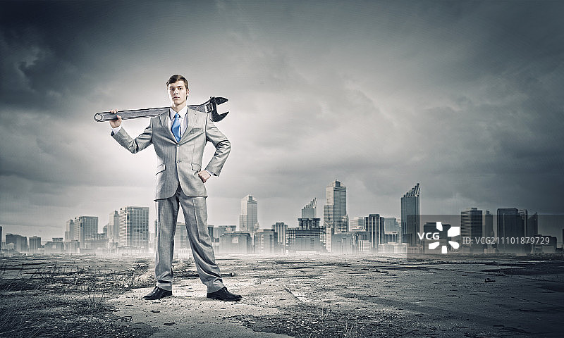 工作机制：年轻商人用扳手在城市背景下工作图片素材