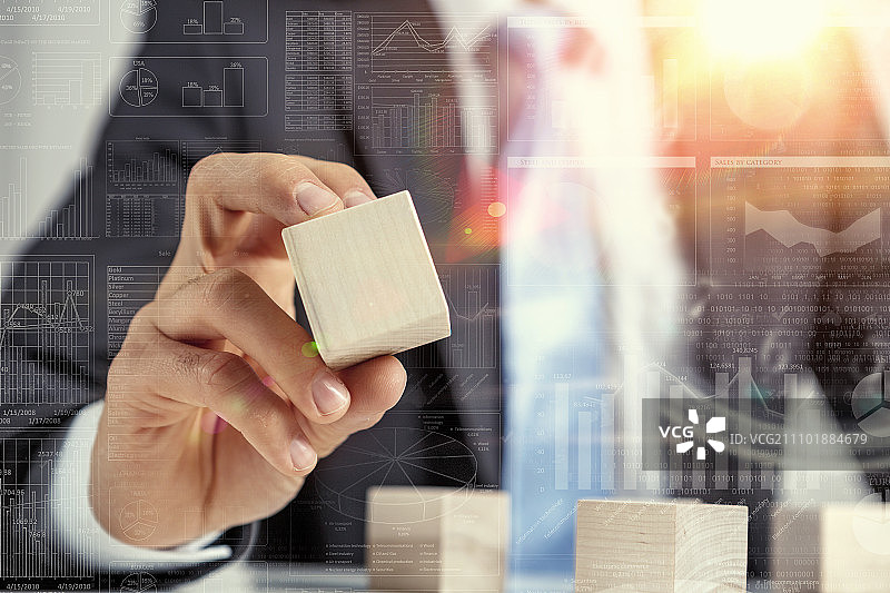 他正在发展他的业务。商人用空木立方体制作金字塔的特写镜头图片素材