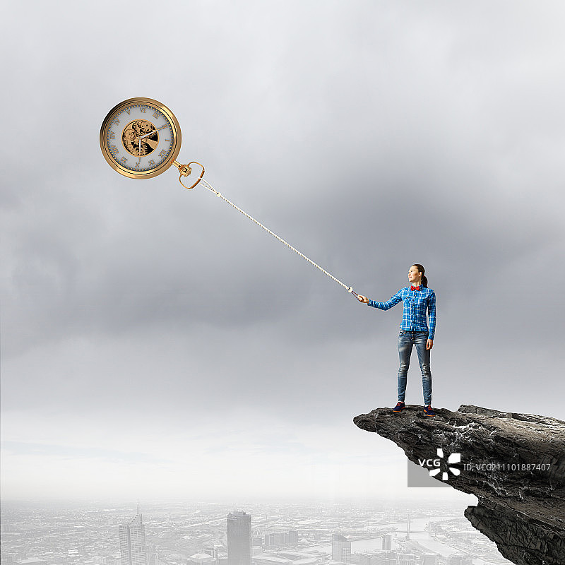 时间流逝：休闲装扮的年轻女子用绳子抓住时钟图片素材