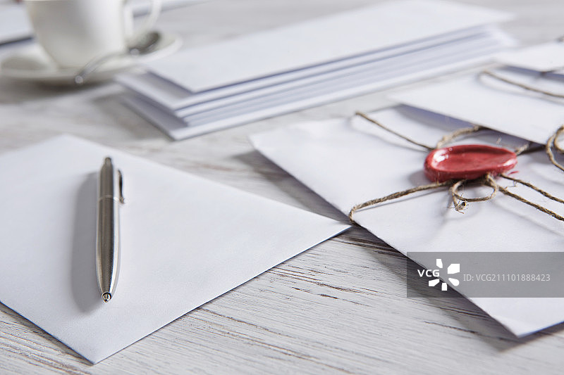 桌上带有封印的信件：带有蜡封的信封和木质表面上的空白纸张图片素材