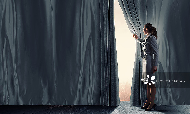 年轻女商人拉开舞台幕布，开启新的机遇图片素材