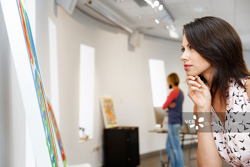 年轻的白人女子站在美术馆的画作前图片素材