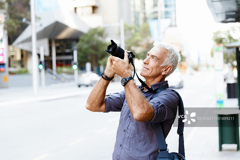 在城市里寻找拍摄地点的年长男人图片素材