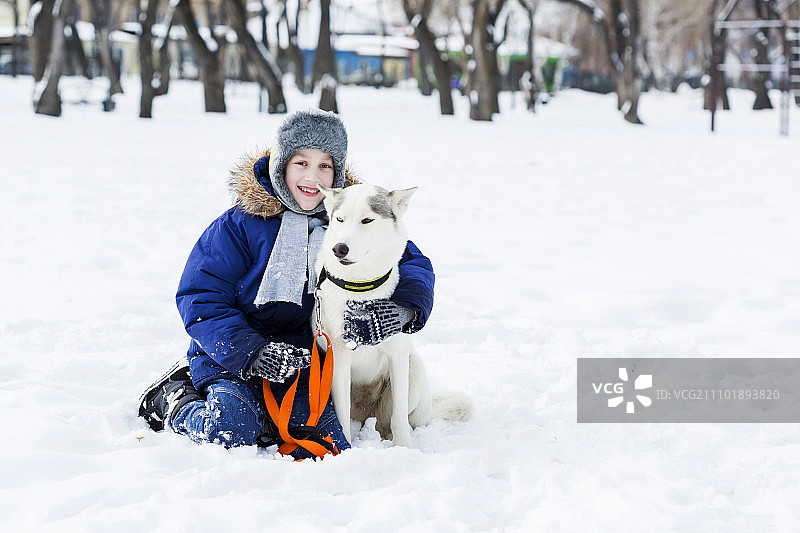 学龄儿童与小狗在冬季公园里，我最好的朋友和我图片素材