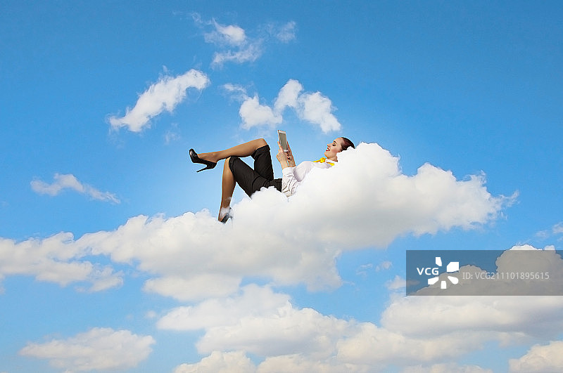 女商人躺在云端，手持平板电脑图片素材